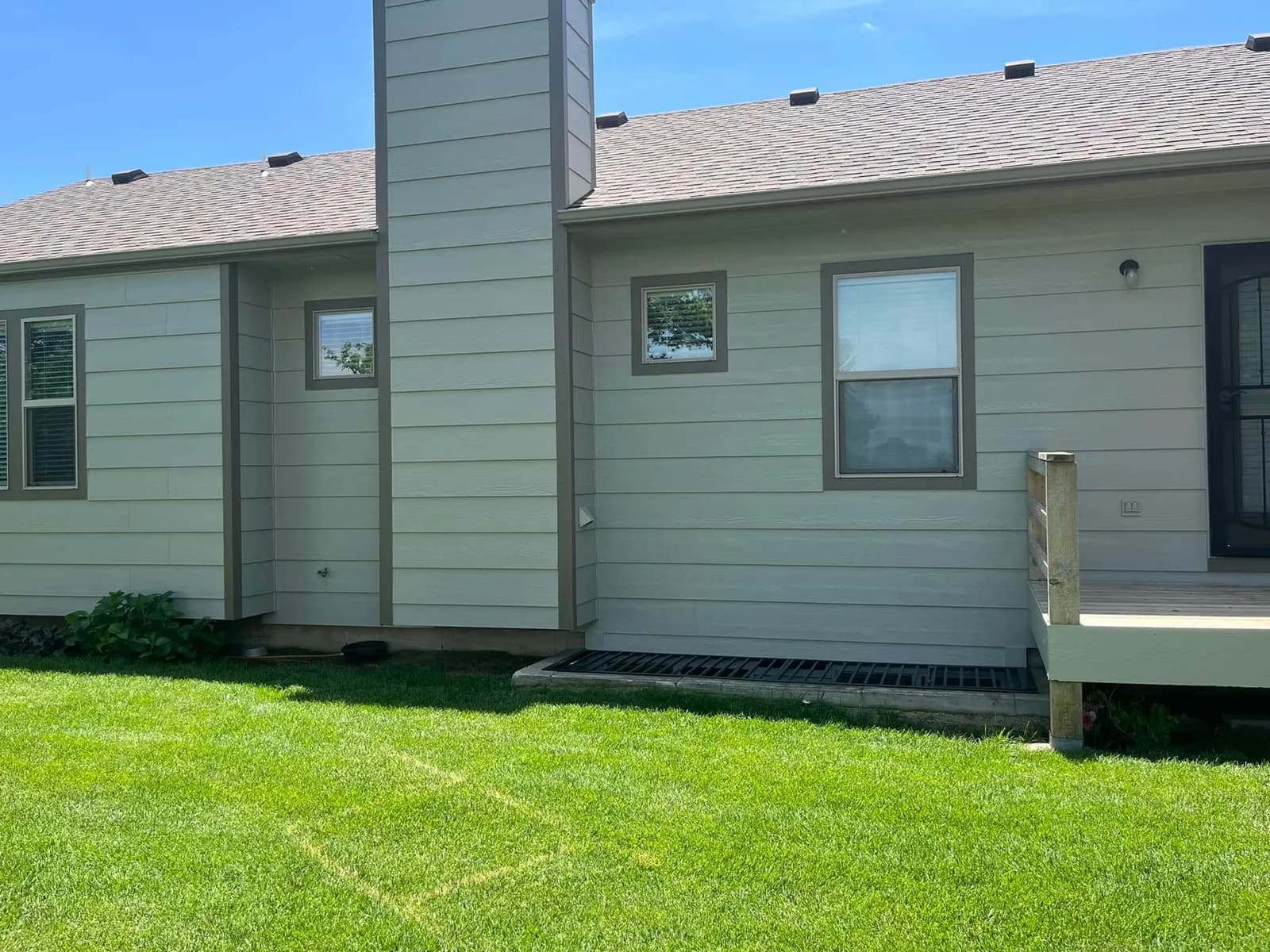 Finished exterior repaint on a Wichita home, sage siding with darker trim around the windows