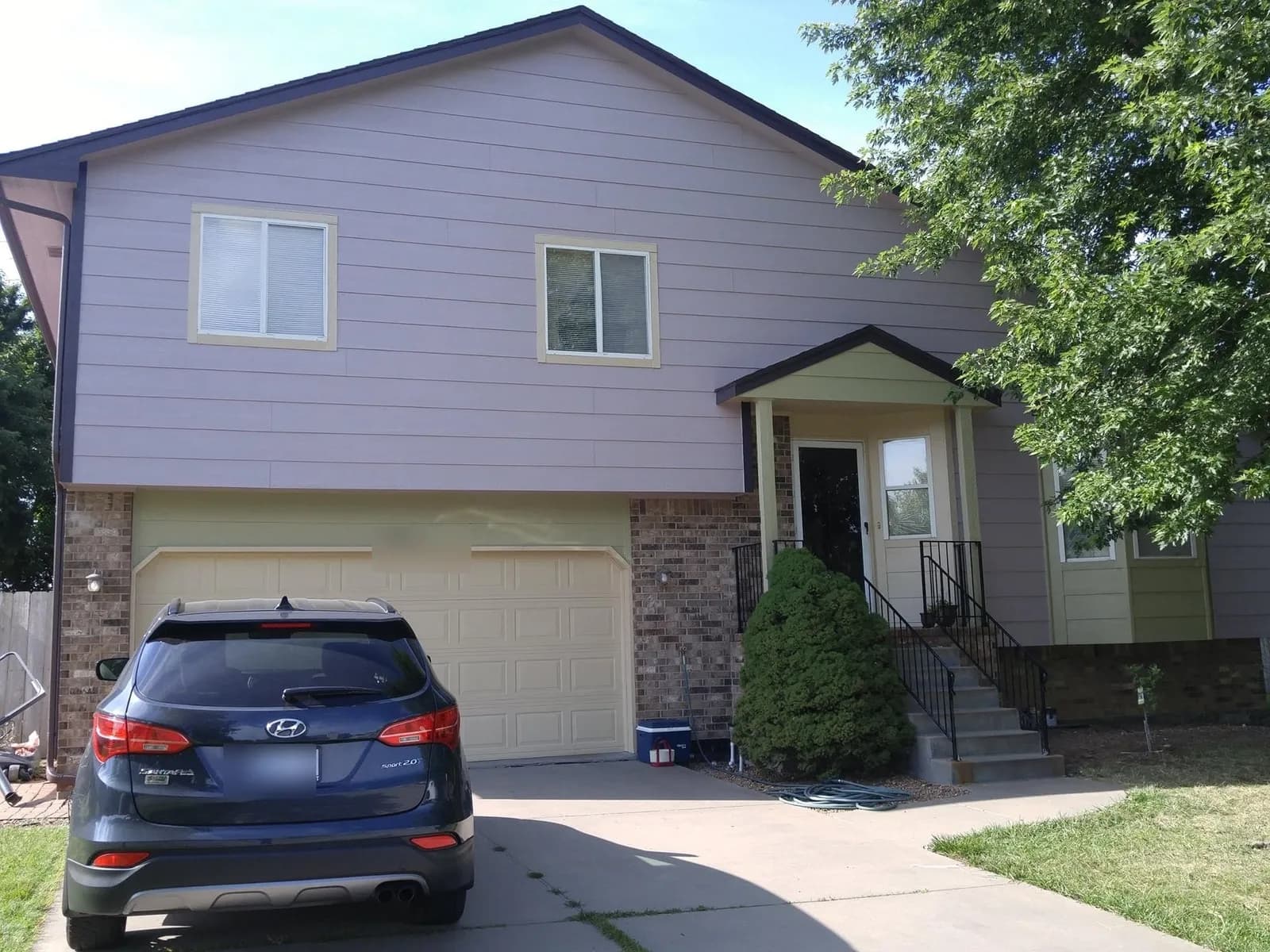 The same home after repainting in soft lavender grey with a cream garage door and trim