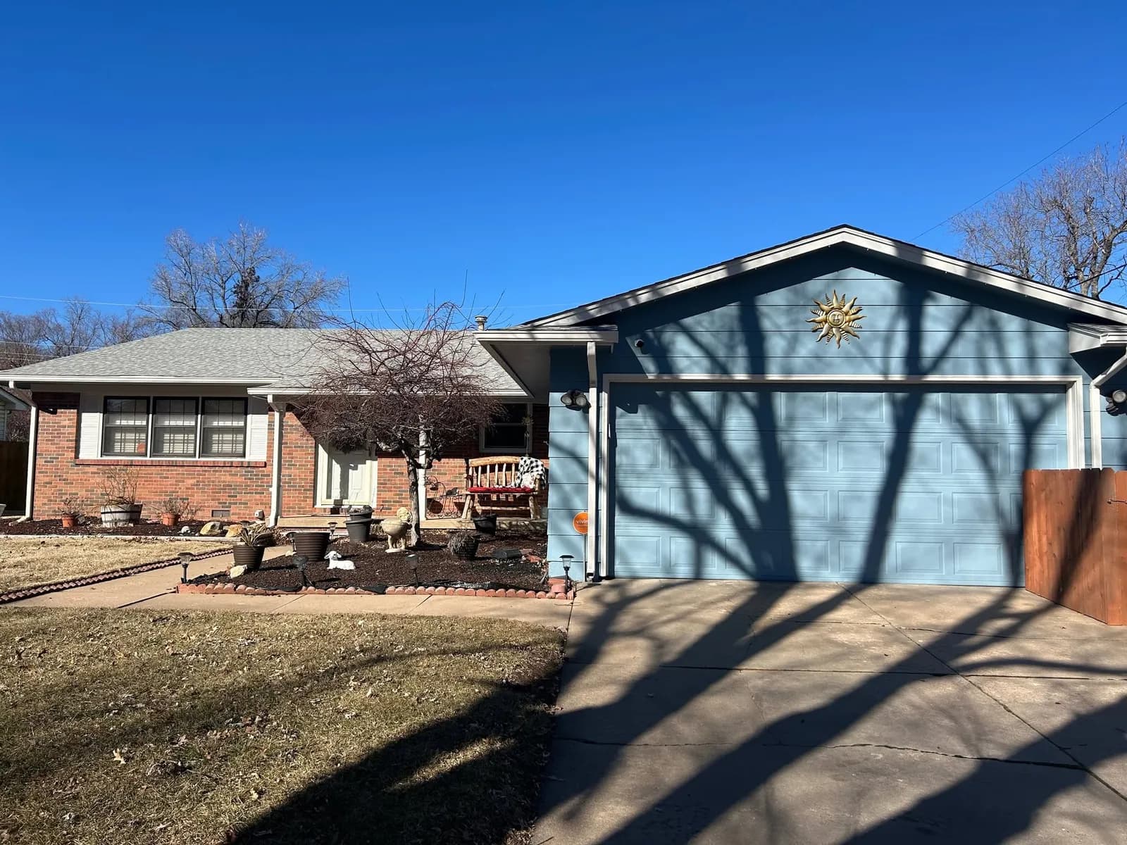 The same brick ranch after repainting, with a blue grey garage door and matching trim