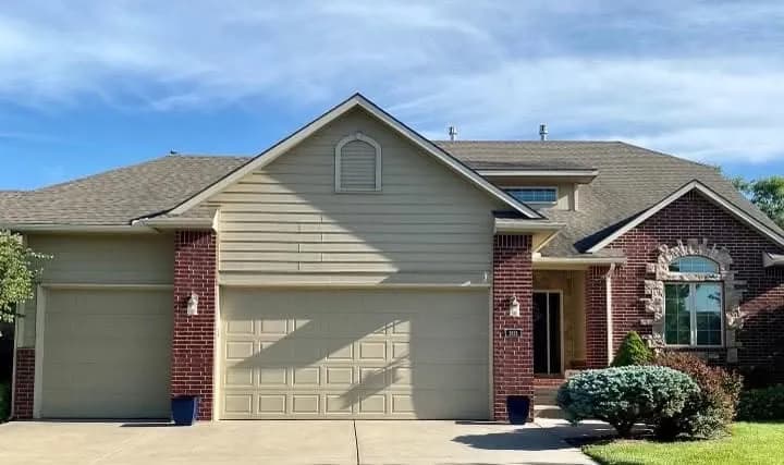 Two-story Wichita home before repainting, in beige siding with a cream garage door